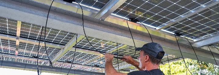 Mann montiert Solarpanele an Carport
